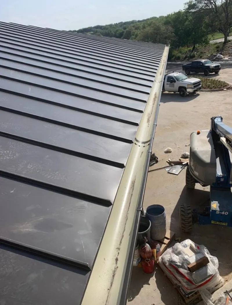 Standing seam panel and gutter detail on a metal roofing jobsite in Forney